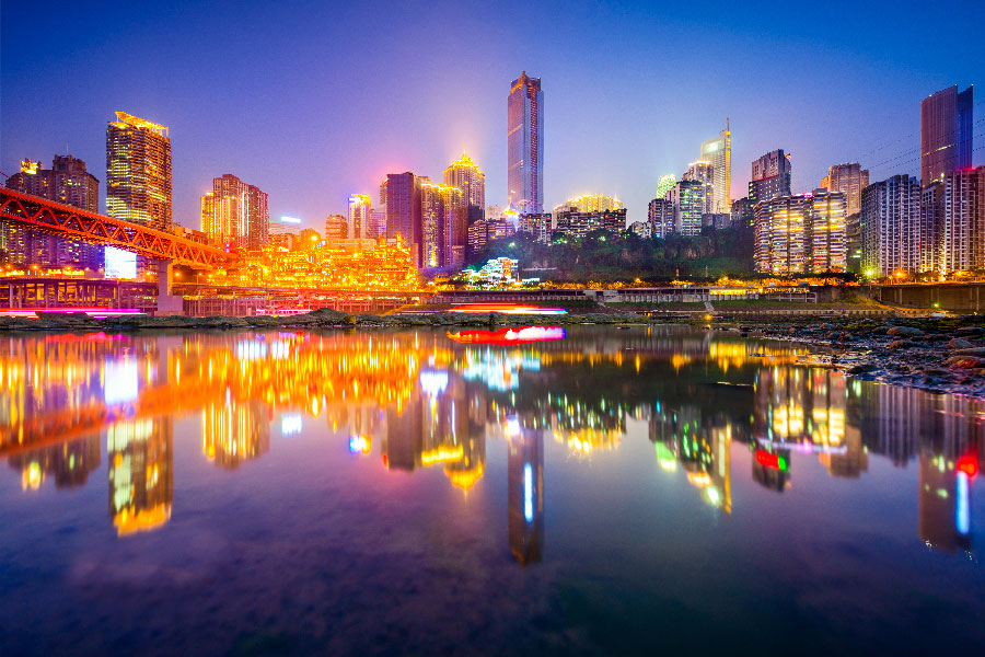 Ciudad de noche iluminada con varias luces de colores a la orilla del río