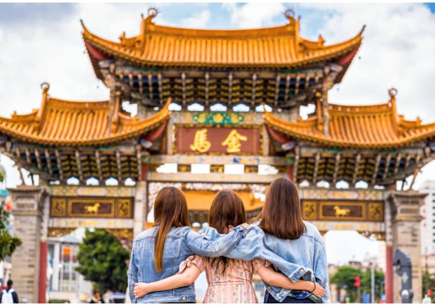 Tres mujeres de espalda abrazándose y mirando un templo chino